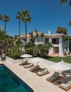 una piscina con sillas y sombrillas junto a una casa en LVone, Villa in Los Verdiales, Golden Mile, en Marbella
