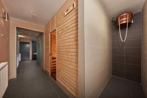 baño con ducha a ras de suelo y pared de azulejos en ProFamily Hotel TOP Benecko, en Benecko