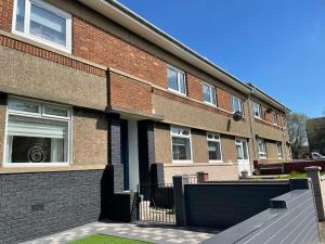 a brick building with a fence in front of it at New boutique 3 bedroom apartment in Hamilton in Hamilton