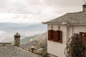 a white building with windows and a view of a valley at The Fern House in Makrinitsa