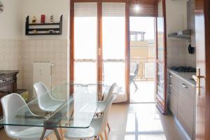 une table en verre dans une cuisine avec des chaises blanches dans l'établissement 093 - Casa Panorama, Vista Mare e Vista Portofino, 500 metri centro di Chiavari, POSTO AUTO GRATIS INCLUSO, à Chiavari