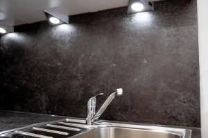 a kitchen sink with a faucet and a black wall at Reos Hotel Wangen in Wangen im Allgäu