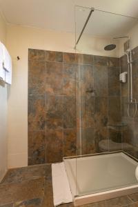 a bathroom with a shower with a bath tub at Hôtel & Restaurant La Ferme Du Pommeau in La Plaine des Palmistes