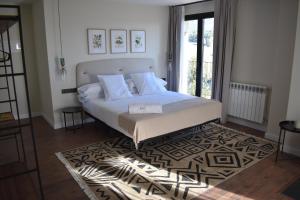 a bedroom with a large white bed with a rug at Duruelo Mountain Suites in Duruelo de la Sierra