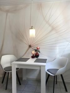 Ferienappartement Greiff في Könen: طاولة بيضاء مع كرسيين و مزهرية بها ورد