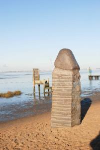 een stenen pilaar op het strand met een stoel in het water bij Appenzeller, S u A , Ferienwohnung Dangaster Tied 2 in Dangast