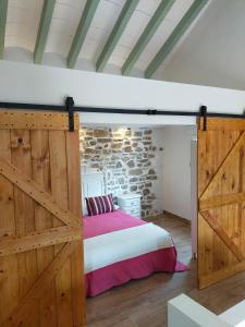 um quarto com uma cama e uma porta de celeiro de madeira em LA CASA DE LA HUERTA Stylish family cottage in Malaga countryside em Málaga