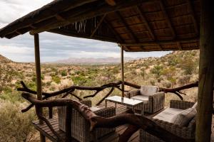 a porch with chairs and a table and a view of the desert at Kapps Mountain Self Catering Accommodation in Voigtland