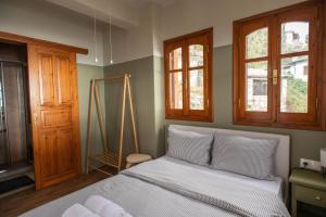 a bedroom with a bed with white sheets and windows at The Fern House in Makrinitsa