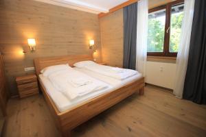 a bedroom with a bed with white sheets and a window at Zell am See Lake View Apartment in Zell am See