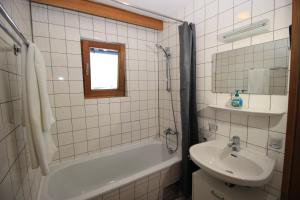 Un baño de azulejos blancos con lavabo y bañera. en Zell am See Lake View Apartment, en Zell am See 26 fotos más