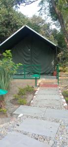 a black tent with a green bench in a park at Corbett Nature Retreat in Rāmnagar