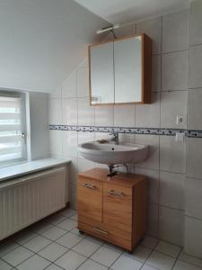 a bathroom with a sink and a wooden cabinet at Oome Tilles Hüs in Norddorf