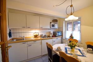 a kitchen with a table and a kitchen with white cabinets at Oome Tilles Hüs in Norddorf +24 photos