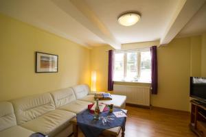 a living room with a white couch and a table at Oome Tilles Hüs in Norddorf