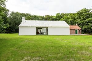 una casa blanca con un gran patio de césped en Coccinelle, en Biggekerke