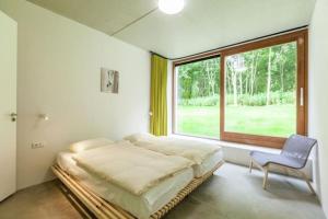 Cama en habitación con ventana y silla en Coccinelle, en Biggekerke