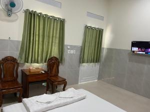 baño con 2 sillas, mesa y TV en Khách sạn Hoàng Gia - TT Lai Vung, en Lai Vung