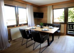 Un comedor con mesa y sillas y ventanas. en Zell am See Lake View Apartment, en Zell am See