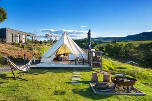 a tent in a field with two chairs and a table at Cicada Luxury Camping in Kiama