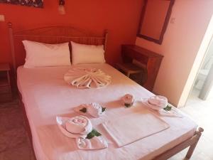 ラガナスにあるLaganas Beach Hotelのベッド(ピンクのタオル、ピンクのバラ付)