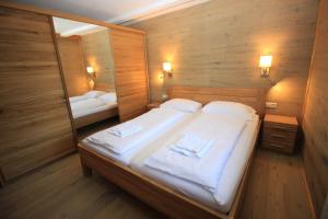 Un dormitorio con una cama con sábanas blancas y un espejo. en Zell am See Lake View Apartment, en Zell am See