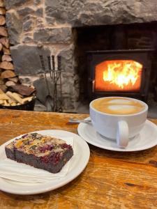 uma fatia de bolo e uma chávena de café numa mesa com lareira em Saucy Mary's Hostel em Kyleakin