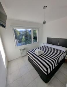 a bedroom with a black and white bed and a window at Bariloche Modern Apartment Belgrano in San Carlos de Bariloche