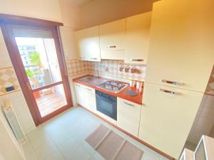 una piccola cucina con armadi bianchi e una finestra di Casa Relax con Terrazza Panoramica a Fiumicino