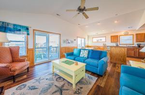 Carolina Cottage في كيتي هوك: غرفة معيشة مع أرائك زرقاء وطاولة