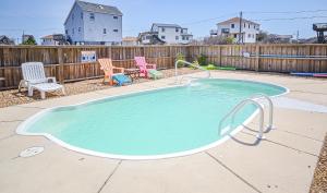 a small pool in a yard with chairs and a fence at Carolina Cottage in Kitty Hawk