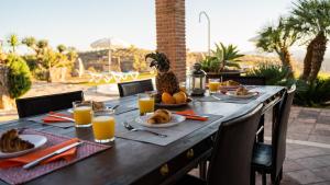 - une table en bois avec de la nourriture et du jus d'orange dans l'établissement Casa Rural Los Menhires, à Malaga