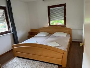 1 Schlafzimmer mit einem Holzbett und 2 Fenstern in der Unterkunft Ferienhaus Cekic in Erlenbach am Main
