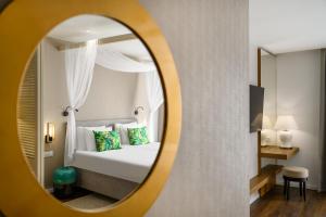 een hotelkamer met een bed en een spiegel bij Mövenpick Balaland Resort Lake Balaton in Szántód