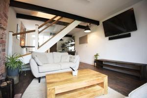 a living room with a white couch and a tv at Industrial Cosy Cottage – Gateway to the Lakes in Newbiggin