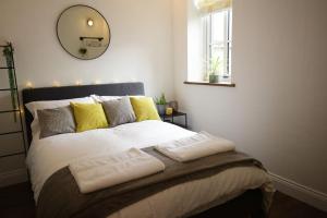 a bedroom with a large bed with yellow pillows and a mirror at Industrial Cosy Cottage – Gateway to the Lakes in Newbiggin