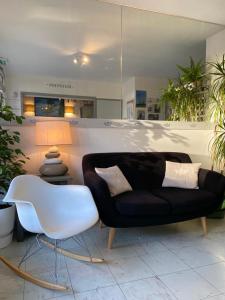 a living room with a black couch and a white chair at hotel l'échappée d'oléron in Saint-Georges-dʼOléron