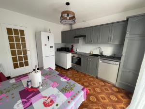 a kitchen with gray cabinets and a table with a table cloth at Super maison entre paris et Disney in Chelles