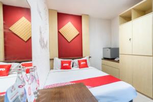 a bedroom with a bed and a red wall at SUPER OYO Flagship 91963 Series Style Hotel in Putat-wetan