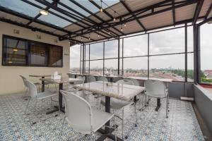 Urbanview Hotel Cantee Halim Perdanakusuma by RedDoorz في جاكرتا: غرفة طعام بها طاولات وكراسي ونوافذ كبيرة