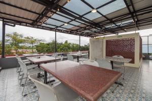 Urbanview Hotel Cantee Halim Perdanakusuma by RedDoorz في جاكرتا: مطعم بطاولات وكراسي بيضاء ونوافذ