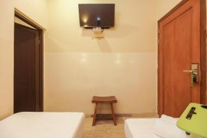 a room with two beds and a tv on the wall at Urbanview Hotel Cantee Halim Perdanakusuma by RedDoorz in Jakarta