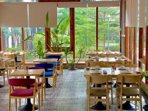 a dining room with tables and chairs and windows at Nakasang Paradise Hotel in Nakasong