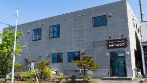 ein graues Gebäude mit einem Schild, das Straßenhotel Masoya liest in der Unterkunft Guesthouse Masago in Urakawa