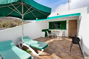 a patio with a green umbrella and chairs and a table at Mar de Lava Sunrise Fuerteventura in Pozo Negro