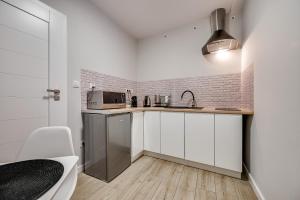 eine weiße Küche mit einer Spüle und einer Mikrowelle in der Unterkunft Central Platinum Apartments 19 in Rybnik