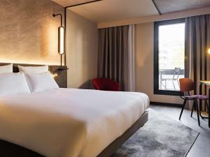 um quarto de hotel com uma cama grande e uma janela em Novotel Paris Suresnes Longchamp em Suresnes