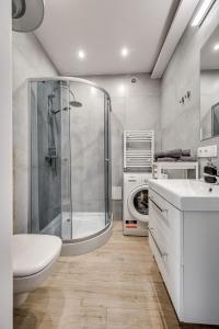 y baño con ducha, lavabo y lavadora. en Central Platinum Apartments 31, en Rybnik