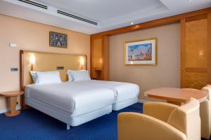 una camera d'albergo con letto, tavolo e sedie di NH Atlantic Den Haag a L'Aia