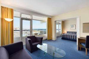 a hotel room with a couch and a bed and window at NH Atlantic Den Haag in The Hague